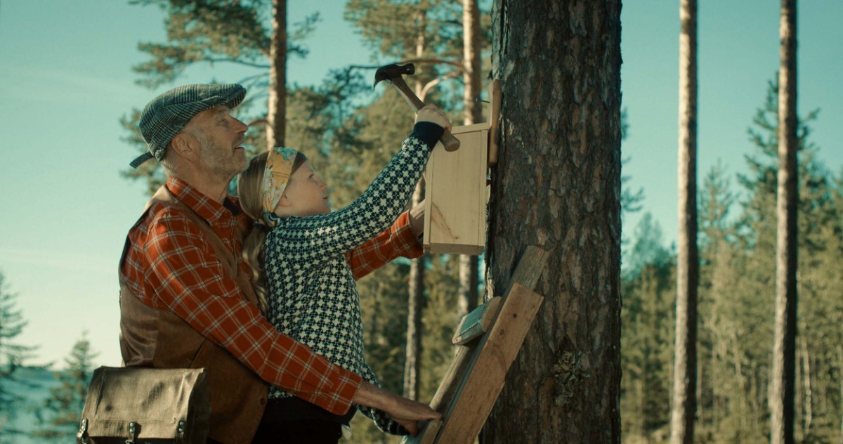 Äldre man med barn sätter upp fågelholk